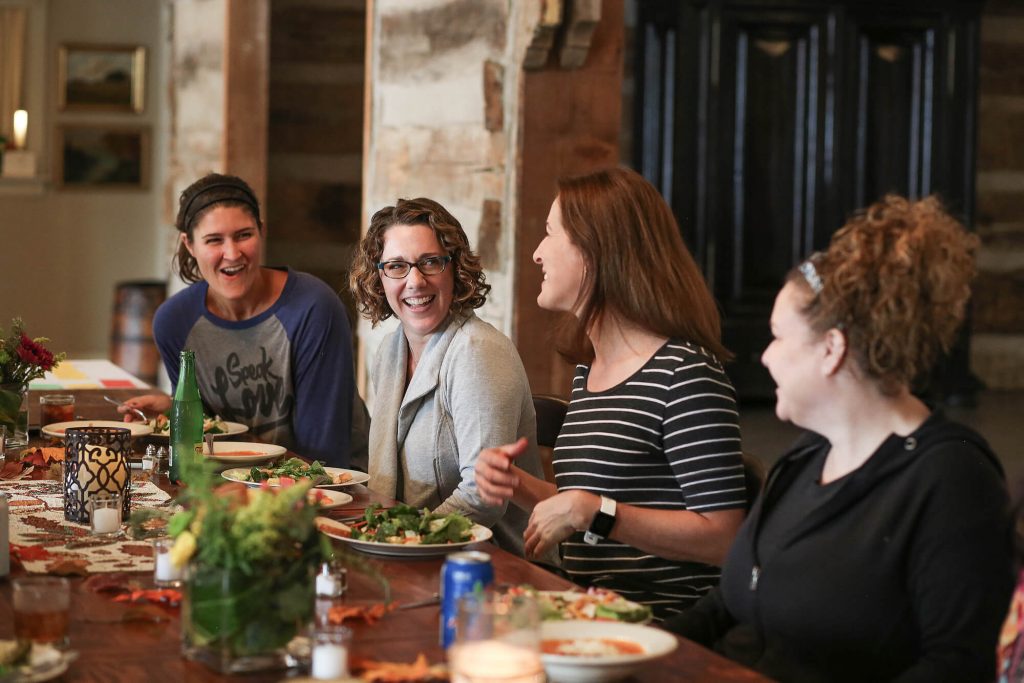 Group of women smiling and laughing at dinner